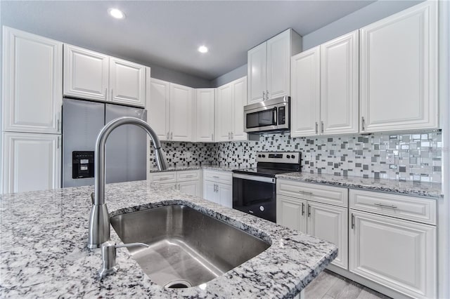 kitchen with tasteful backsplash, stainless steel appliances, white cabinetry, and sink