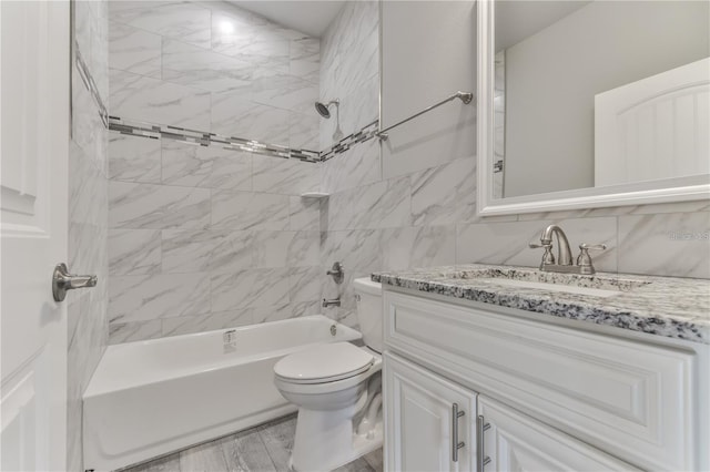 full bathroom featuring toilet, tiled shower / bath combo, vanity, hardwood / wood-style floors, and tile walls