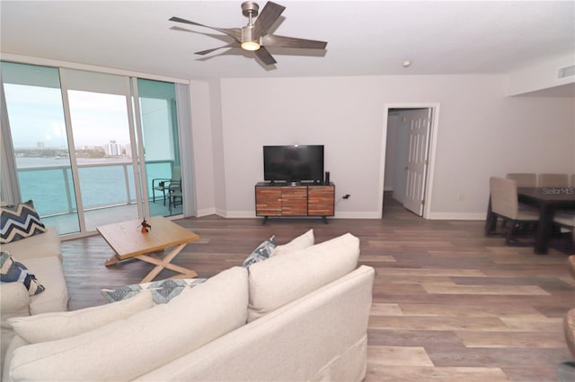 living room with dark hardwood / wood-style floors, ceiling fan, and a wall of windows