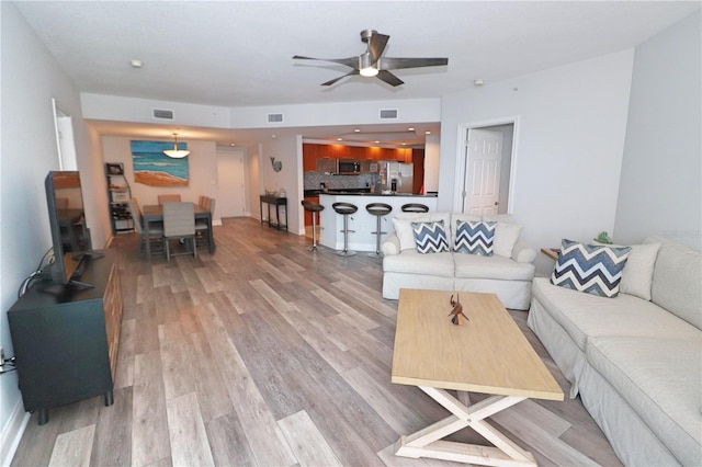 living room with light hardwood / wood-style floors and ceiling fan