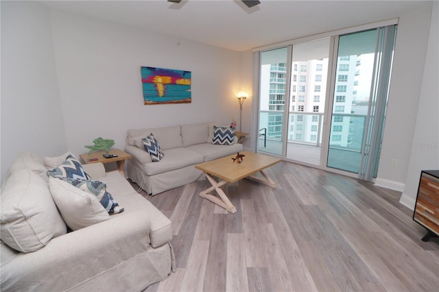 living room featuring floor to ceiling windows, ceiling fan, and light hardwood / wood-style flooring