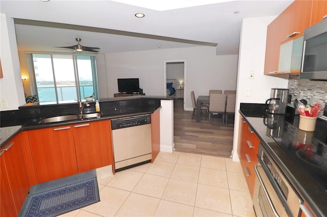 kitchen featuring ceiling fan, a water view, light hardwood / wood-style flooring, white dishwasher, and tasteful backsplash