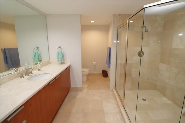 bathroom featuring toilet, tile floors, a shower with shower door, and vanity with extensive cabinet space