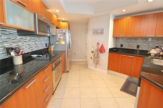 kitchen featuring light tile floors, tasteful backsplash, a raised ceiling, and stainless steel appliances