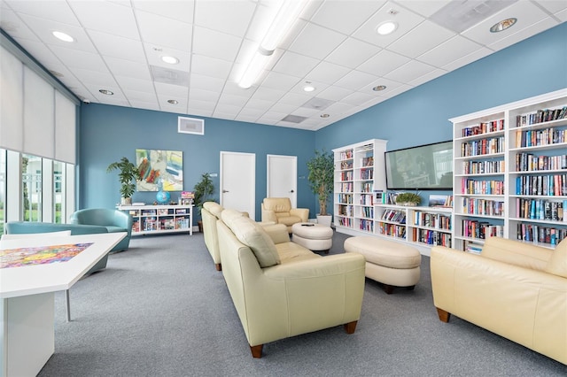 living room featuring carpet flooring and a paneled ceiling