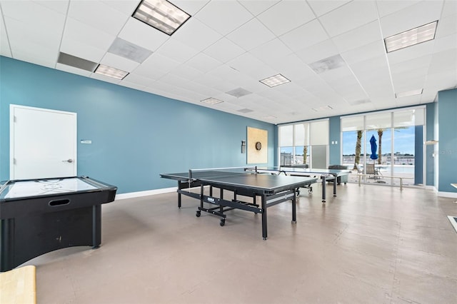 playroom featuring a paneled ceiling and a wall of windows