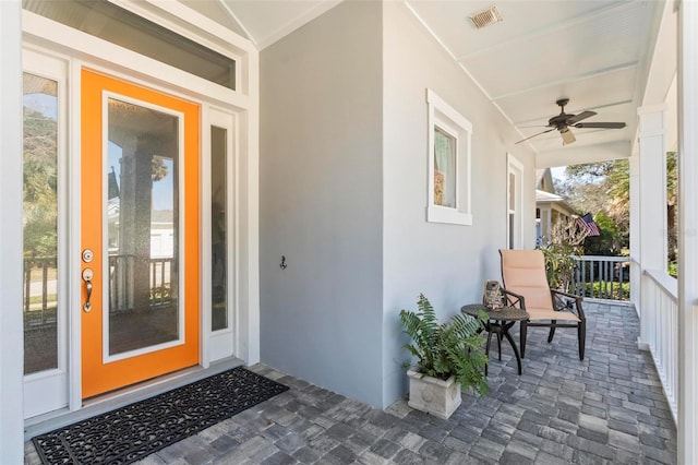 view of exterior entry with a porch and ceiling fan