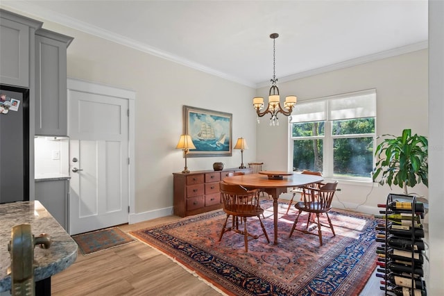 dining room with ornamental molding, light wood-type flooring, and an inviting chandelier