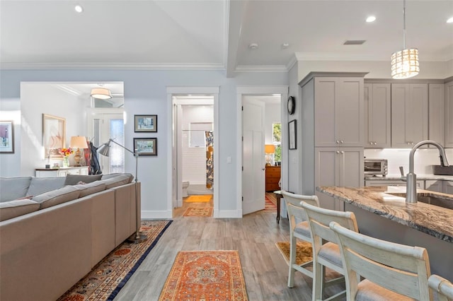 interior space featuring light hardwood / wood-style floors, gray cabinets, pendant lighting, and light stone countertops