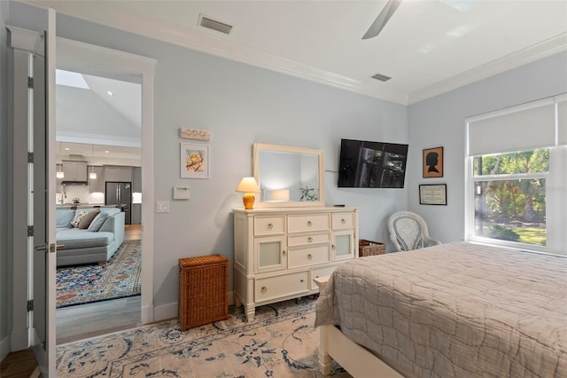 bedroom featuring ceiling fan, crown molding, light hardwood / wood-style flooring, stainless steel refrigerator, and lofted ceiling