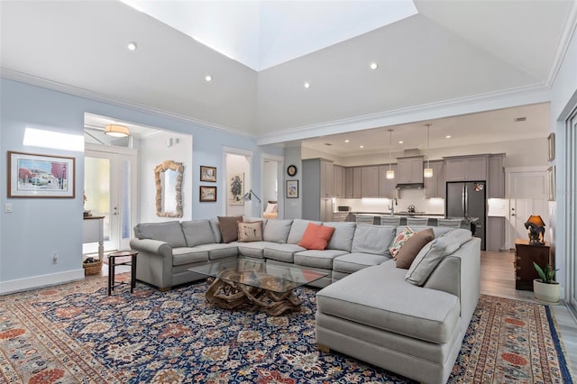 living room with crown molding, high vaulted ceiling, sink, and light wood-type flooring