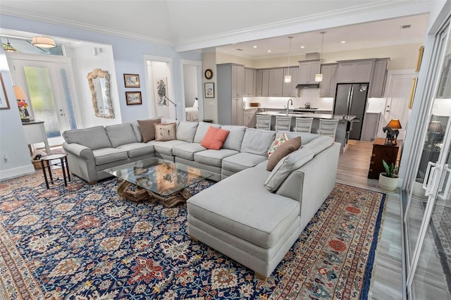 living room featuring ornamental molding, light wood-type flooring, and sink