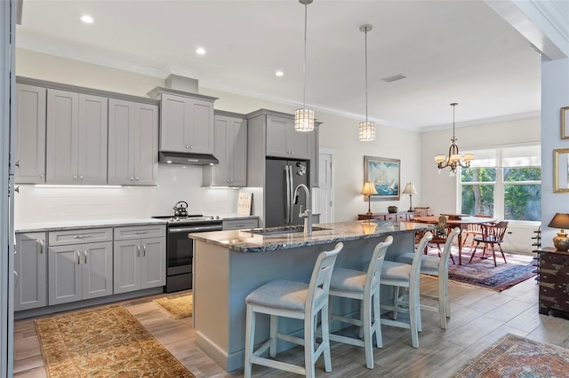 kitchen featuring decorative light fixtures, a chandelier, gray cabinets, and stainless steel appliances