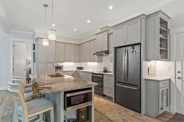 kitchen featuring light stone counters, hanging light fixtures, appliances with stainless steel finishes, backsplash, and light hardwood / wood-style floors