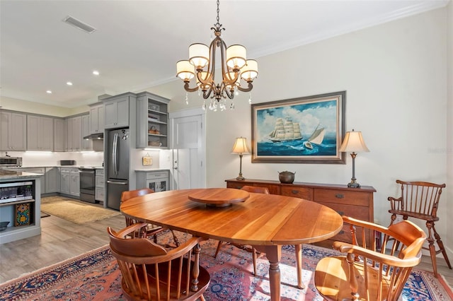 dining room featuring a chandelier, crown molding, and light hardwood / wood-style flooring