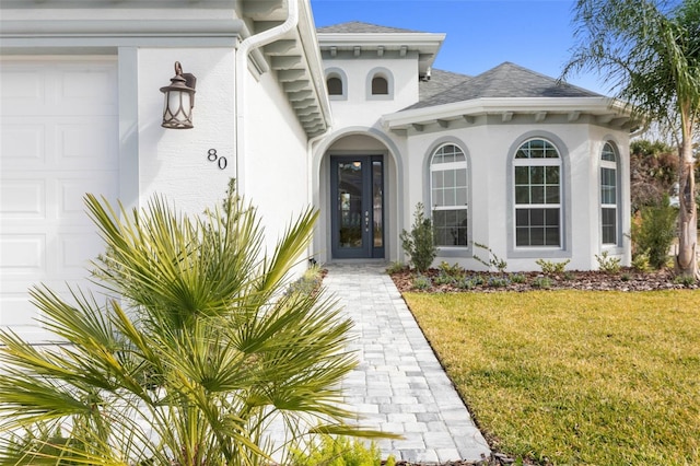 view of exterior entry with a yard, french doors, and a garage