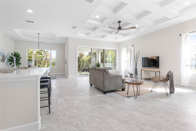 living room featuring beam ceiling, coffered ceiling, ceiling fan with notable chandelier, and light tile floors