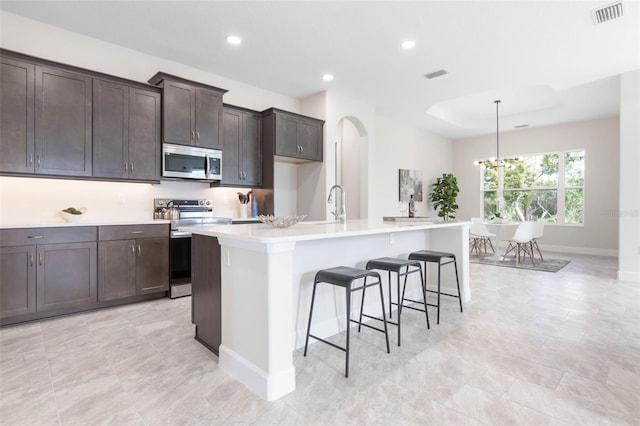 kitchen featuring a kitchen island with sink, pendant lighting, electric range, a chandelier, and light tile flooring