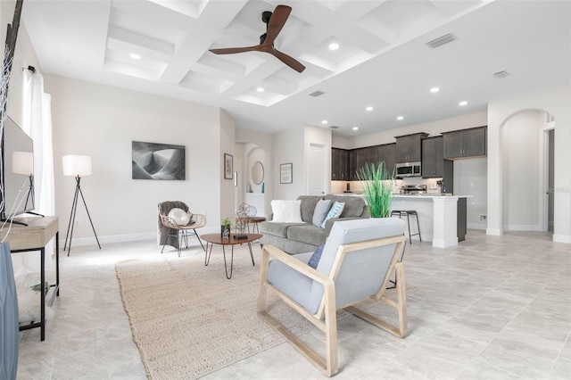 living room featuring coffered ceiling, ceiling fan, light tile flooring, and beamed ceiling