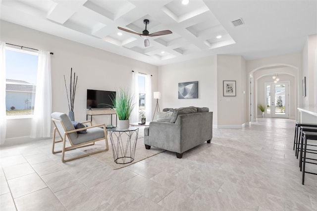 tiled living room with coffered ceiling, ceiling fan, french doors, and beamed ceiling