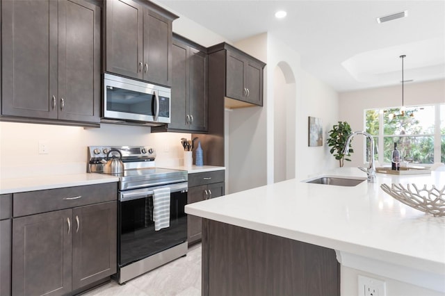 kitchen with sink, light tile floors, stainless steel appliances, decorative light fixtures, and a notable chandelier