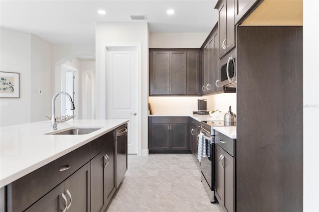 kitchen featuring stainless steel appliances, light tile flooring, sink, and dark brown cabinetry