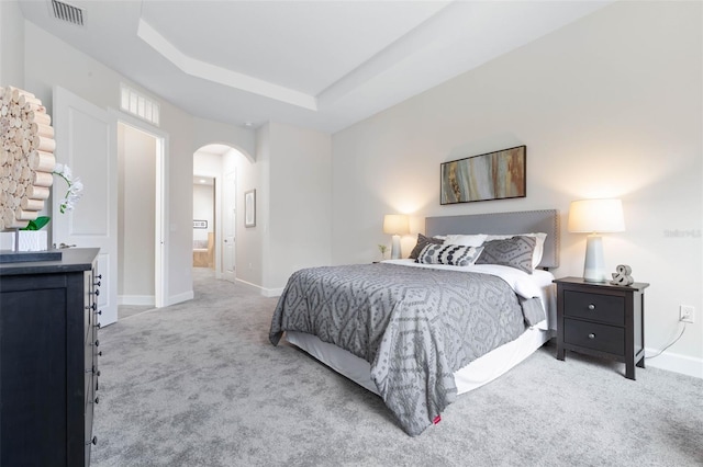 bedroom featuring light carpet and a tray ceiling