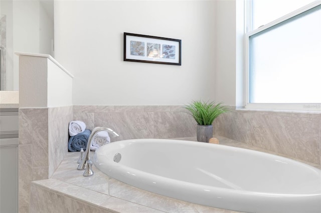 bathroom featuring tiled bath and vanity