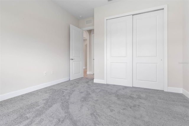 unfurnished bedroom with light colored carpet and a closet