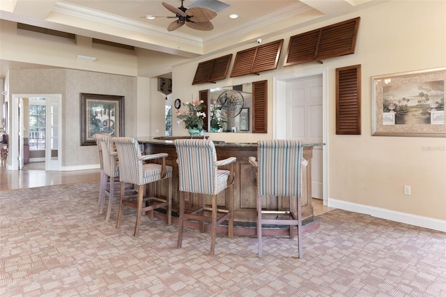 bar featuring a raised ceiling, crown molding, light tile flooring, and ceiling fan