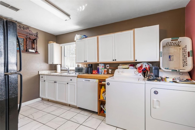 clothes washing area with light tile flooring, washing machine and clothes dryer, and sink