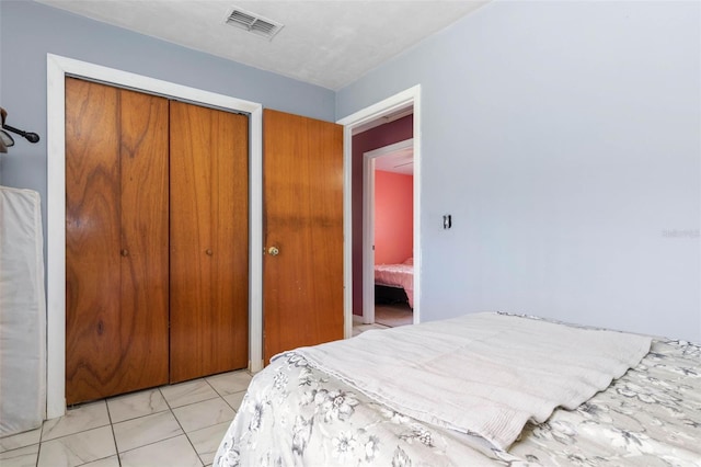 bedroom featuring visible vents, a closet, and light tile patterned flooring