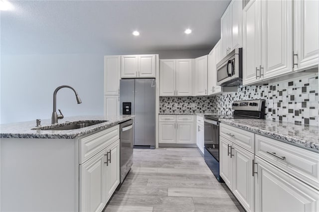 kitchen with white cabinetry, stainless steel appliances, sink, and light hardwood / wood-style flooring