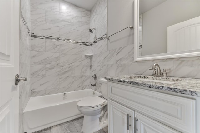 full bathroom featuring toilet, tiled shower / bath combo, vanity, wood-type flooring, and tile walls