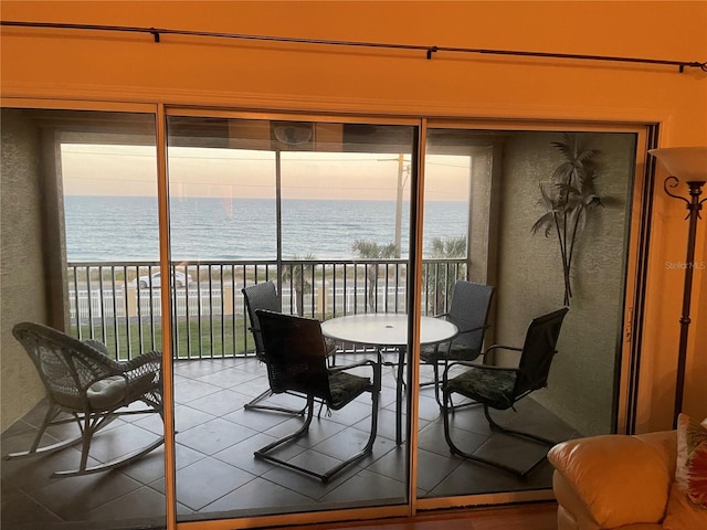 balcony at dusk featuring a water view