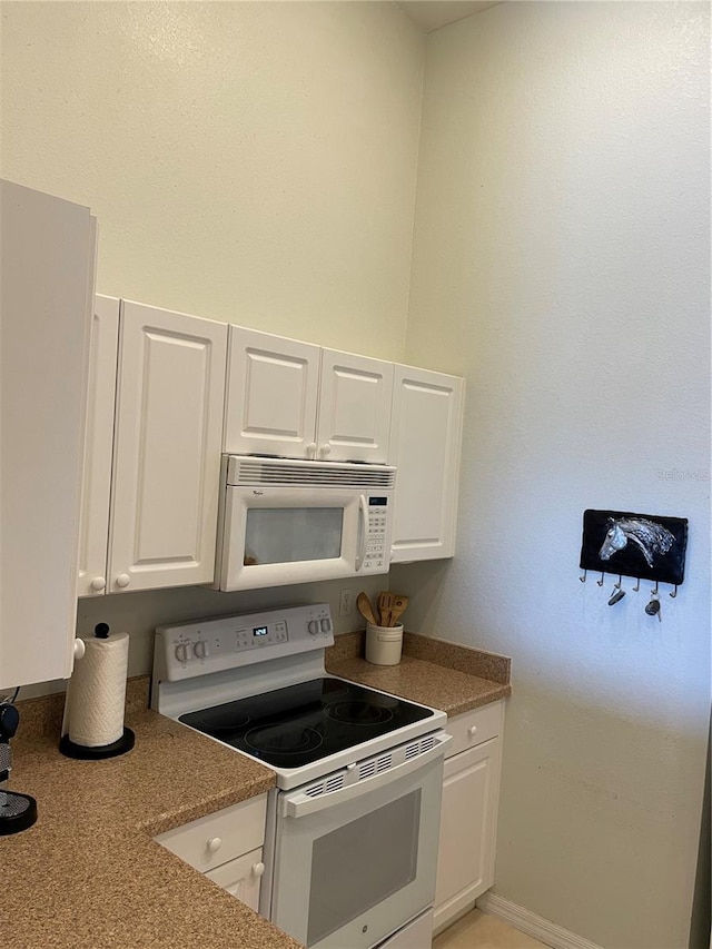 kitchen featuring white appliances, white cabinets, and stone counters