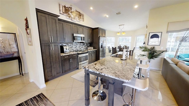 kitchen featuring pendant lighting, stainless steel appliances, a kitchen bar, tasteful backsplash, and sink