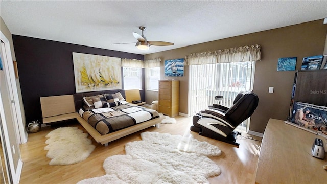 bedroom with a textured ceiling, multiple windows, light hardwood / wood-style floors, and ceiling fan