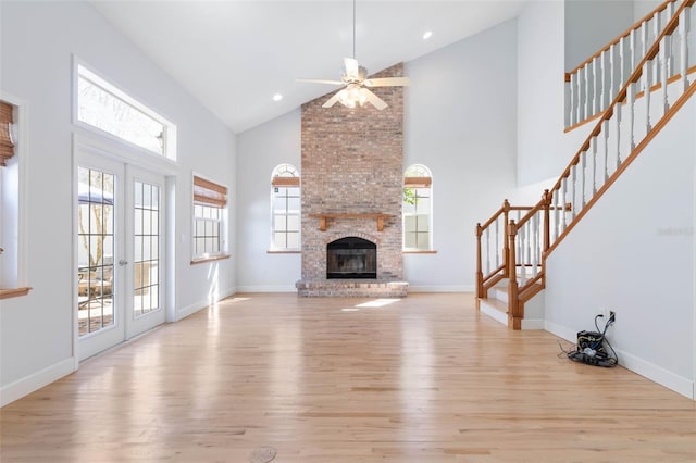 unfurnished living room with high vaulted ceiling, light hardwood / wood-style floors, a fireplace, and a wealth of natural light