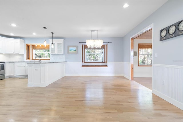 kitchen with hanging light fixtures, backsplash, light hardwood / wood-style flooring, white cabinets, and a chandelier