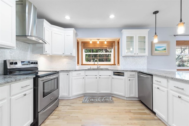 kitchen featuring backsplash, appliances with stainless steel finishes, wall chimney exhaust hood, and sink