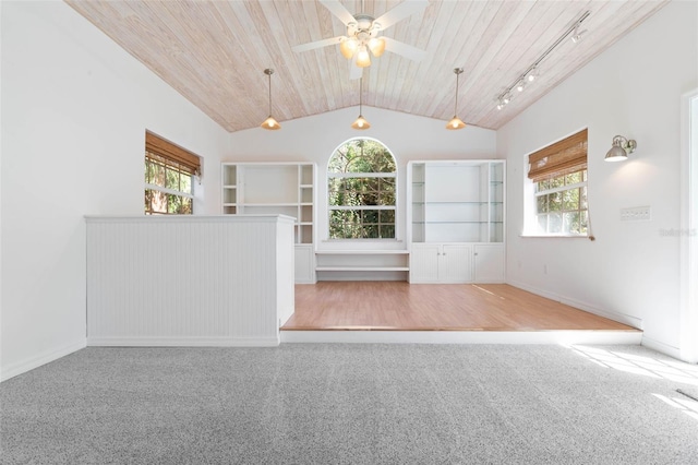 carpeted empty room featuring wood ceiling, rail lighting, ceiling fan, and vaulted ceiling