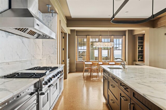 kitchen featuring light stone counters, stainless steel appliances, ventilation hood, pendant lighting, and an inviting chandelier