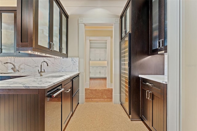 kitchen featuring dark brown cabinets, light stone countertops, sink, and backsplash