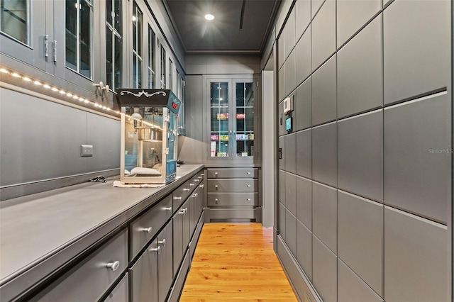 interior space with light hardwood / wood-style flooring, ornamental molding, and gray cabinetry