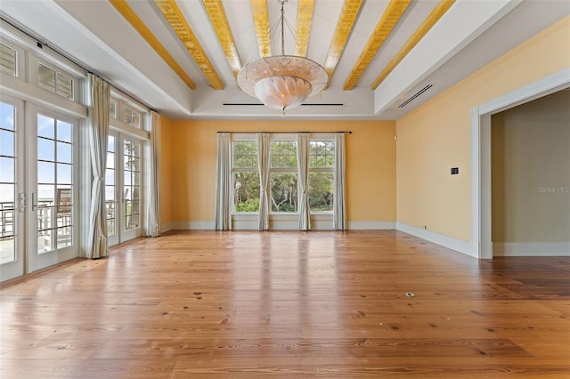 unfurnished room with french doors, light wood-type flooring, beam ceiling, and a wealth of natural light