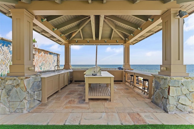 view of patio / terrace with a gazebo, a water view, an outdoor kitchen, and sink