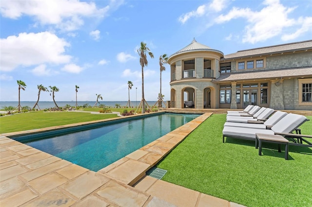 view of swimming pool with a water view, a patio, and a yard