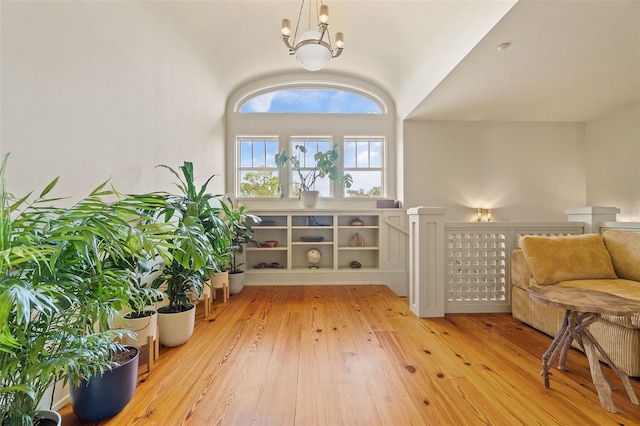 sitting room featuring hardwood / wood-style flooring, lofted ceiling, and an inviting chandelier