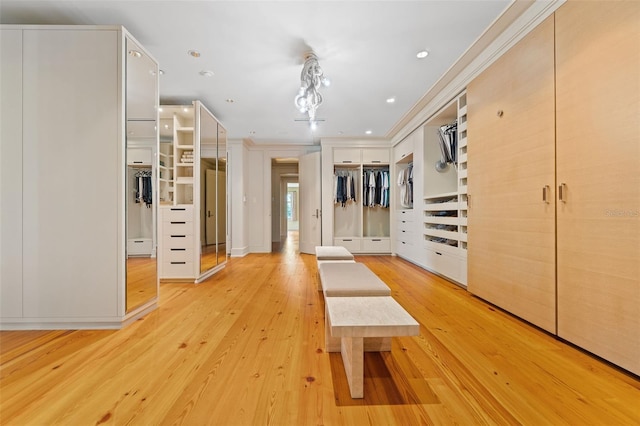 hallway with a notable chandelier, crown molding, and light hardwood / wood-style flooring